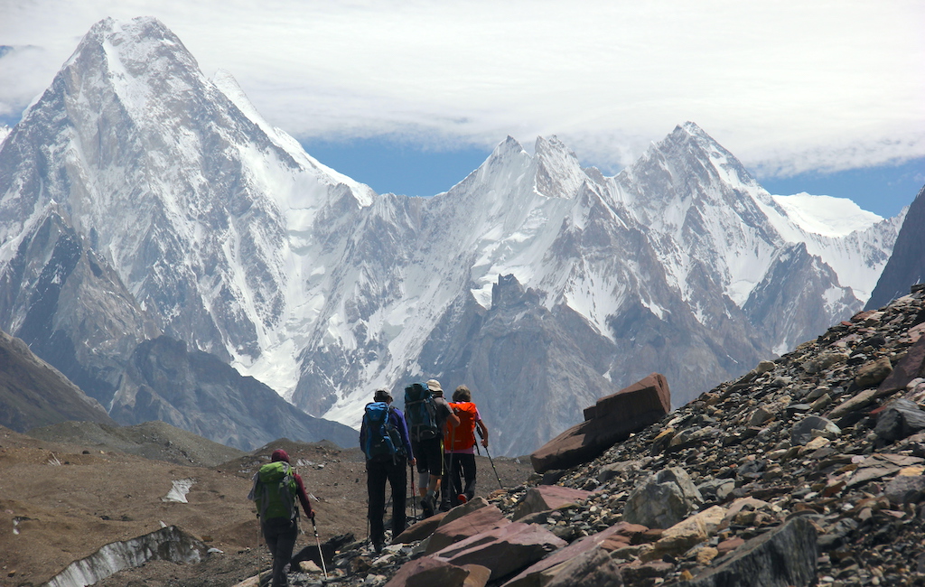 Grup d’excursionistes fent trekking a la Glacera de Baltoro, amb muntanyes nevades imponents com a teló de fons.